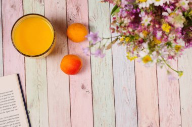 Kahvaltı masası, meyveler, meyve suyu kitabı ve çiçekler, renkli arka plan.