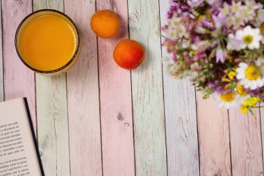 Kahvaltı masası, meyveler, meyve suyu kitabı ve çiçekler, renkli arka plan.