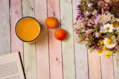 Kahvaltı masası, meyveler, meyve suyu kitabı ve çiçekler, renkli arka plan.