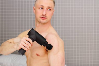 Adam evde mashine tabancasıyla masaj yapıyor.