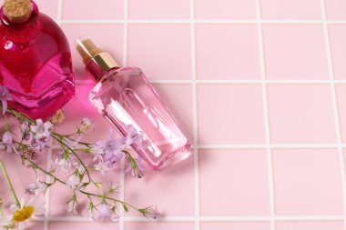 Çiçekli pembe masanın üzerindeki parfüm şişesi.