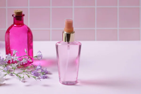 Parfümflasche Auf Rosa Tisch Mit Blumen — Stockfoto