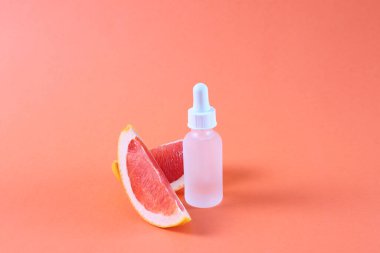 Kozmetik şişesi ve greyfurt, taklit yağ özü sıvısı.