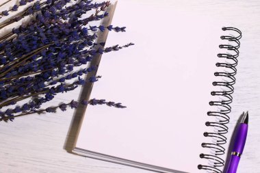 Boş defter kalem ve lavanta çiçekleri masada.