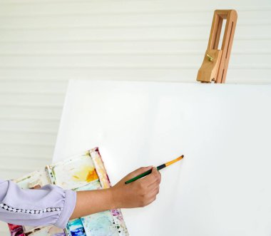 Kapalı el, suluboya resim derslerinde beyaz bir tahta çiziyor.