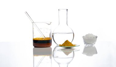 Beaker 'da karıştırıcı çubukla Ferric Chloride Liquid, Flat Bottom Flask' te kristal berrak sıvı, Organik Curcuma Powder ve White flake kimyasalı. Beyaz laboratuvar masasında yakın çekim kimyasal malzeme var..