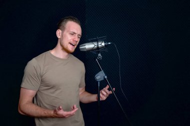 Siyah ses geçirmez duvarların önünde şarkı söyleyen beyaz bir genç. Müzisyenler profesyonel kayıt stüdyosunda müzik yapıyor..