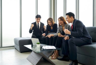 Takım elbiseli bir grup iş adamı, gülümseyen ifadelerle iyi haberlerin heyecanını bildiriyor..