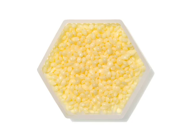 Beyaz arkaplanda altıgen moleküler şekilli konteynırda Candelilla Wax.