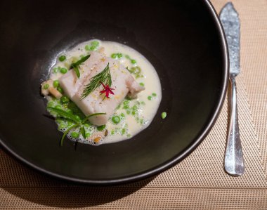 Alaska morinası, bezelye, krema soslu ebiko ve limon. Güzel bir restoranın ana yemek menüsü masada servis edilir..