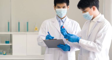Covid-19 testing in laboratory. Two Scientists discuss about blood samples of patients infected with Coronavirus disease 2019. Healthcare and medical concept.
