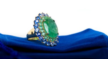 Emerald with Tanzanite ring on dark blue velvet bag. Collection of natural gemstones accessories. Studio shot