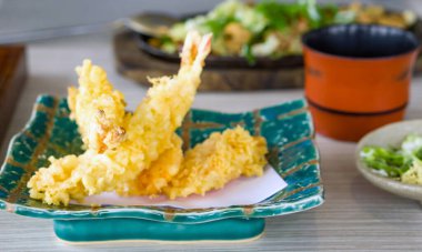 Seramik tabakta kızartılmış karides tempurası. Restorandaki ahşap masada Japon yemeği..