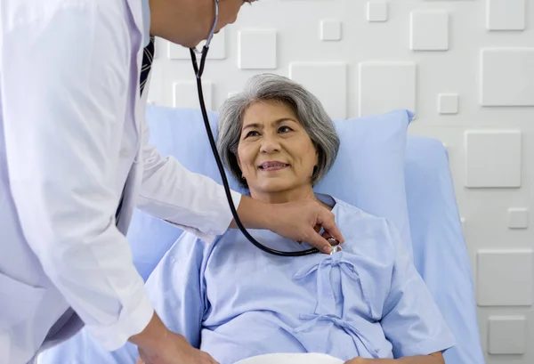 Senior female patient and doctor. Asian doctor use a stethoscope to check the heartbeat of the elderly patient.