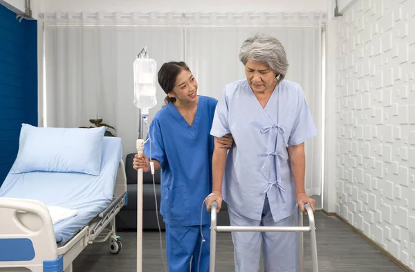 Young asian nurse at nursing home take care disabled senior woman. Caregiver doctor serve physical therapy for elderly patient to exercise and practice walking on walker or cane.