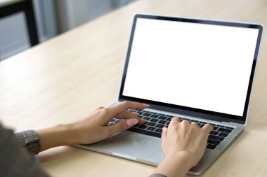 Ekose desenli takım elbiseli bir iş kadınının arka planda oturup dizüstü bilgisayar klavyesinde beyaz ekranla yazı yazması..