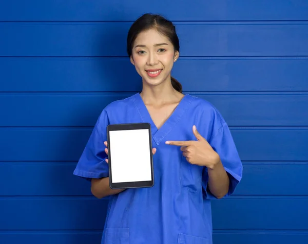 Joven Asiático Médico Azul Uniforme Apuntando Dedo Blanco Pantalla Tableta —  Fotos de Stock