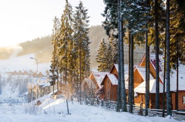 Dağlarda şafak vakti. Gün ışığı ormandaki kayak merkezinin Alp tahta evlerine düşüyor.