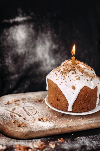 Великодній десерт, прикрашений білою свічкою на дерев'яній дошці . — стокове фото