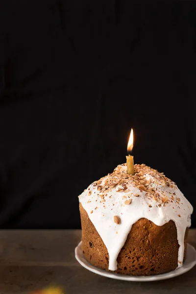 Bolo de Páscoa decorado com cereja branca com uma vela sobre um fundo preto. — Fotografia de Stock