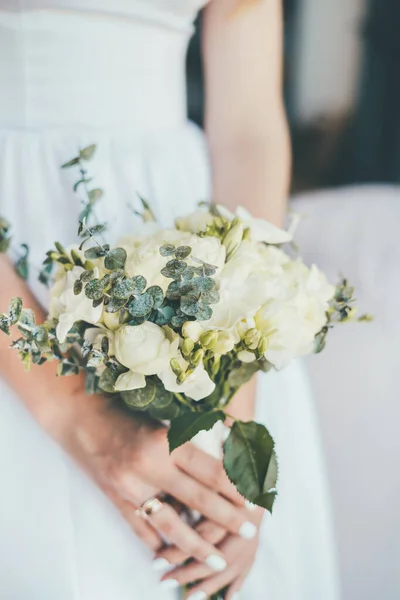 Κοντινό πλάνο ενός όμορφου νυφικού μπουκέτο στα χέρια της νύφης με λευκό φόρεμα. — Φωτογραφία Αρχείου