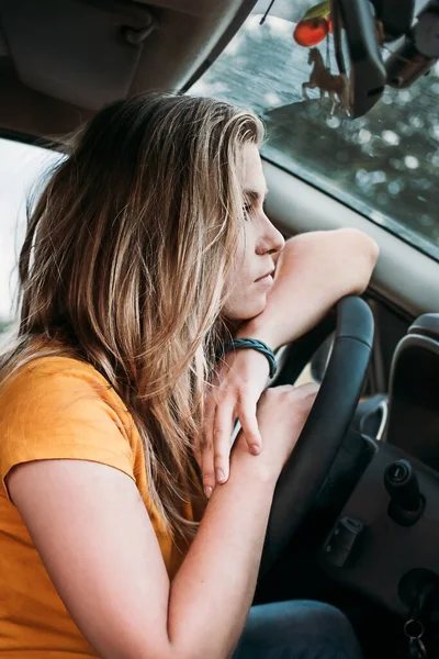 La chica se encuentra en el volante en el coche mirando a la distancia — Foto de Stock