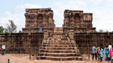 20 Ekim 2021 Konark Güneş Tapınağı, Orissa, Hindistan. BhogaMandapa 'ya ya da dans salonuna hayran olan bir turist. Müzisyen ve dansçıların oymaları neredeyse tüm platformu, duvarları ve koridorun sütunlarını kaplıyor.