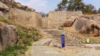 Chitradurga Kalesi 'nin bej rengi duvarları ve farklı işaretleri gösteren bir tabela, Karnataka, Hindistan.  