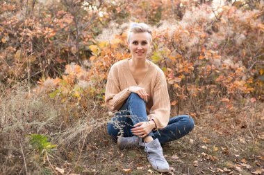 Sonbahar ormanlarında altın ve kırmızı ağaçlı genç bir kadın.