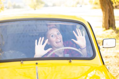 Güz parkında arka planda altın ağaçlarla dolu eski arabadaki tuhaf yüz ifadesi olan kadın.