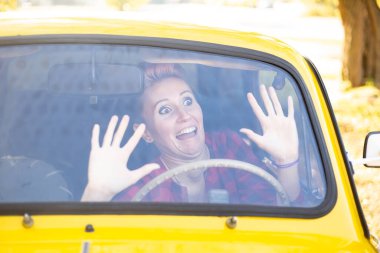 Sonbahar parkında arka planda altın ağaçlarla dolu eski bir arabada korku ifadesi olan kadın.