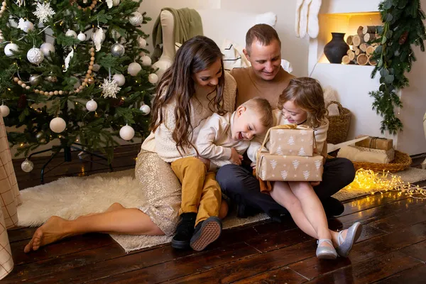 クリスマスツリーの近くの家で遊ぶ床の上の家族 クリスマスプレゼントを背景に — ストック写真