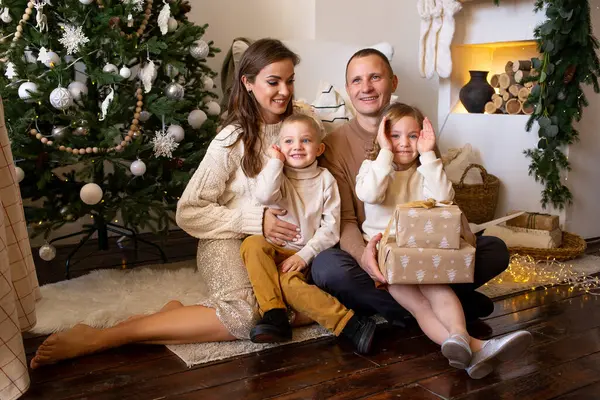 屋内クリスマスツリーの近くにギフトボックスを持つ母と子供 — ストック写真