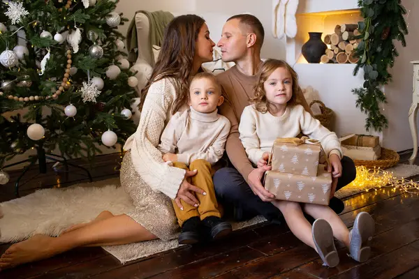 部屋にプレゼントを持った家族を愛する メリークリスマスとハッピーホリデー 親とその小さな子供たちは屋内で楽しんでいます — ストック写真