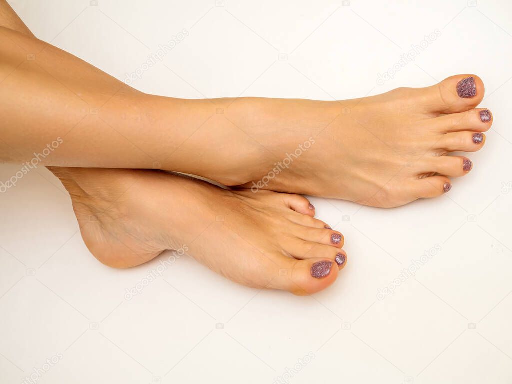 Legs and feet of a young girl with a pedicure on a white background. Close-up.