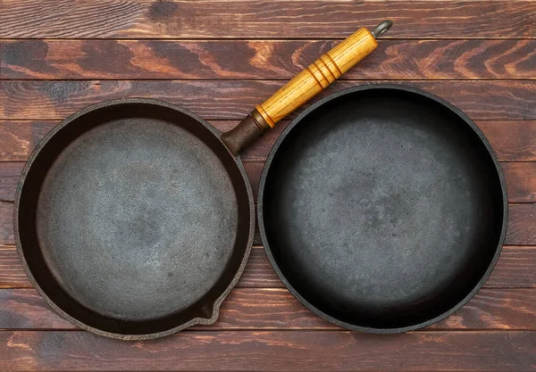 Bir çift demir kızartma kalıbı, arka plandaki karanlık tahtaların üzerine konur..