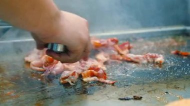 Şef, tavada kızartılmış, dilimlenmiş, lezzetli, gevrek, domuz pastırması pişiriyor. Yavaş çekim dilimlenmiş organik pastırma.. 