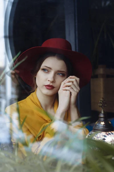Elbiseli ve şapkalı kız pencereden dışarı bakıyor, üzgün, kendini izole, depresyon, salgın — Stok fotoğraf