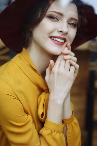 Портрет девушки в кафе с чашкой кофе и шляпным портретом чувственной молодой девушки в мягкой шляпе и блузке с луком. Красивая брюнетка в кафе держит чашку кофе — стоковое фото