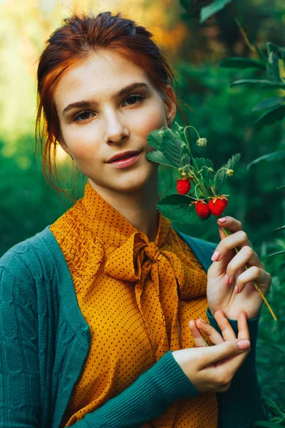 Portret pięknej dziewczyny z brązowymi włosami, która trzyma gałązkę z dzikimi truskawkami. zbiory — Zdjęcie stockowe