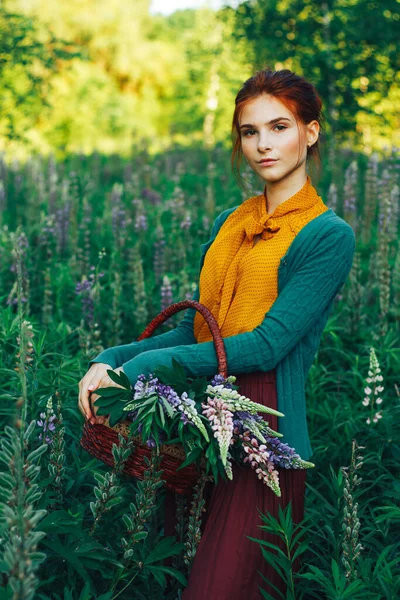 밭의 꽃들 사이에 갈색 머리카락을 가진 아름다운 소녀의 초상화. 여름 방학에 꽃이 핀다. 시골 로열티 프리 스톡 이미지