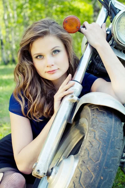 Young beautiful girl sits near the front wheel motorcycle — Stock Photo, Image