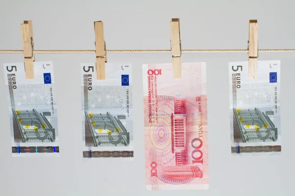 Três de cinco notas de euro e cem yuans face value de pendurar no varal — Fotografia de Stock