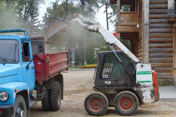 Piccolo escavatore carichi ghiaia in un camion — Foto Stock