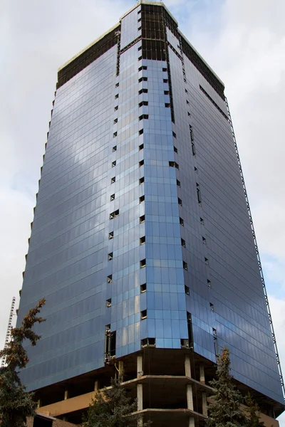 Edificio de varios pisos con una fachada de vidrio durante la construcción — Foto de Stock