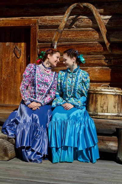 Duas meninas sentadas em um monte de casas de madeira e sussurrar algo — Fotografia de Stock