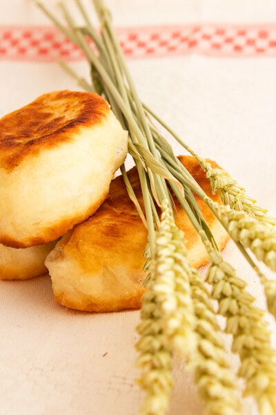 Fried cakes with cabbage and wheat ears on a white napkin