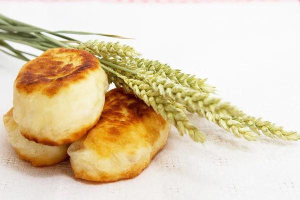 Pasteles fritos con repollo y espigas de trigo en una servilleta blanca —  Fotos de Stock