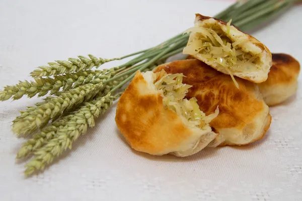 Жареные пироги с капустой и пшеничными ушами на белой салфетке — стоковое фото