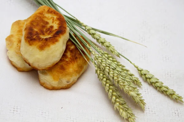 Pasteles fritos con repollo y espigas de trigo en una servilleta blanca —  Fotos de Stock